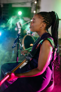young-female-musician-on-stool-playing-electric-guitar